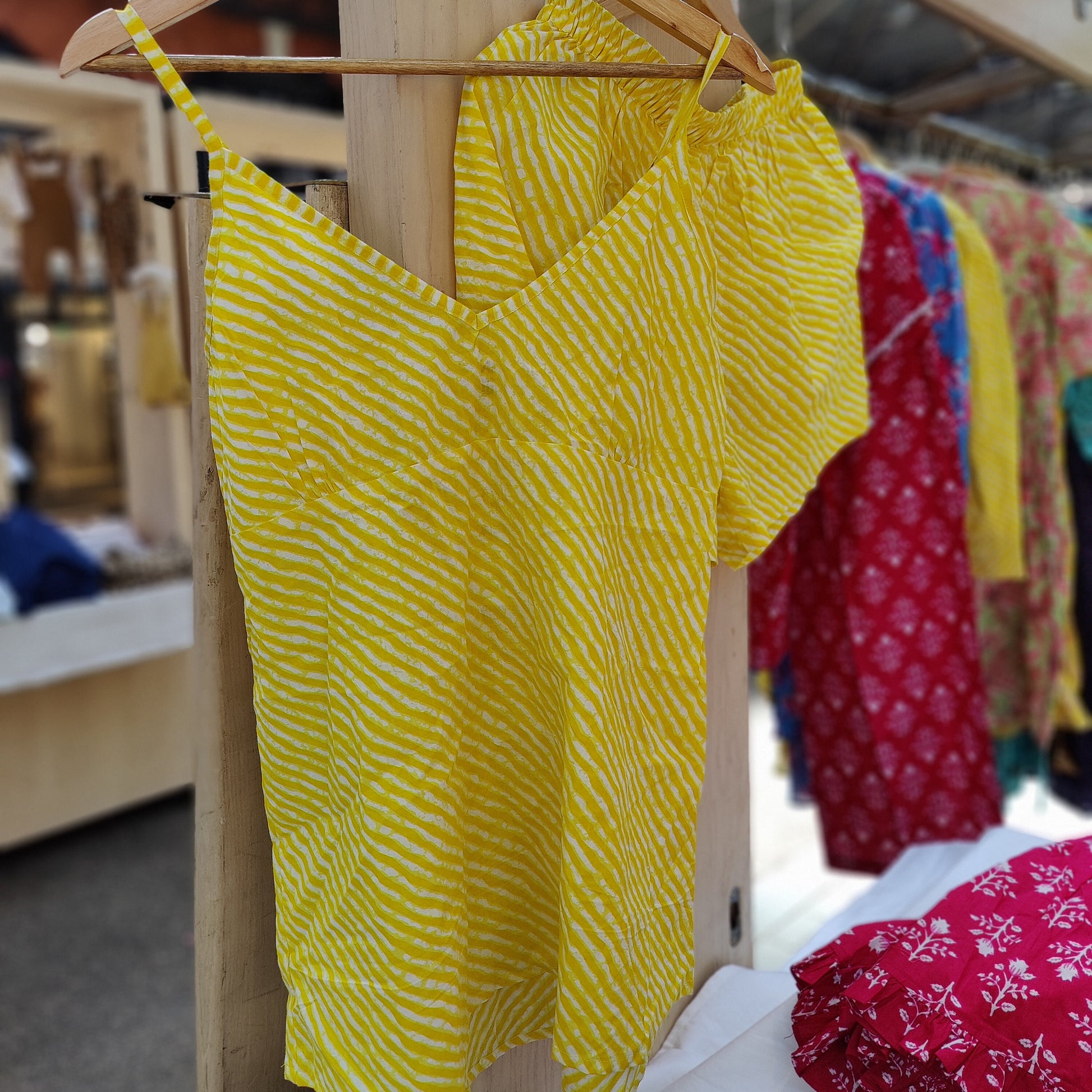 Striped yellow camisole cotton pyjama top with elastic waist shorts on a hanger.