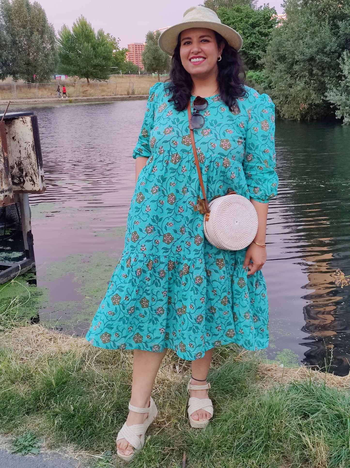 Girl wearing a aquamarine dress standing in front of a canal 