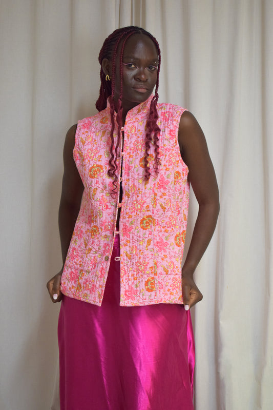 Female model posing in a pink vest and pink skirt.