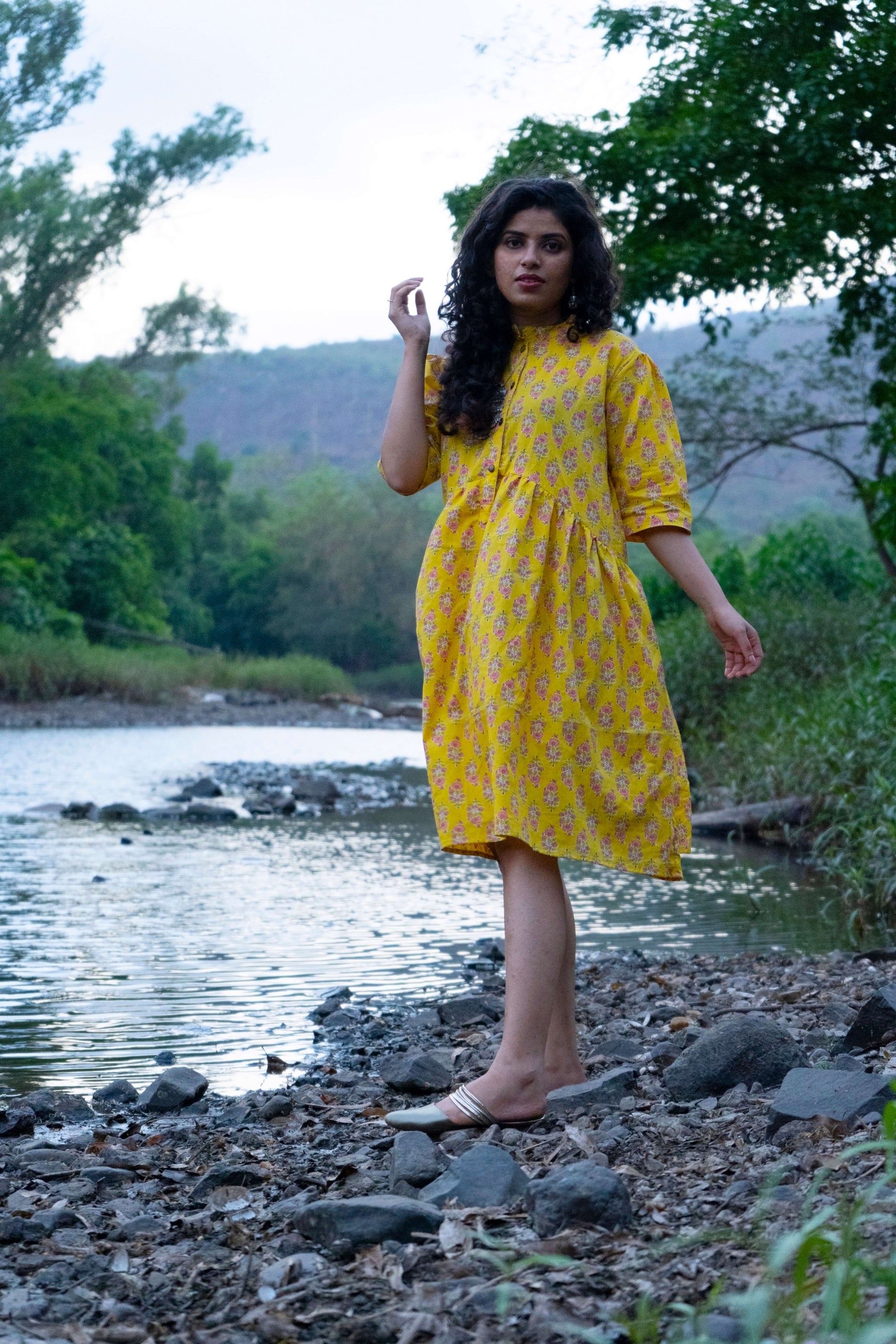 Girl wearing yellow dress near a stream in the woods