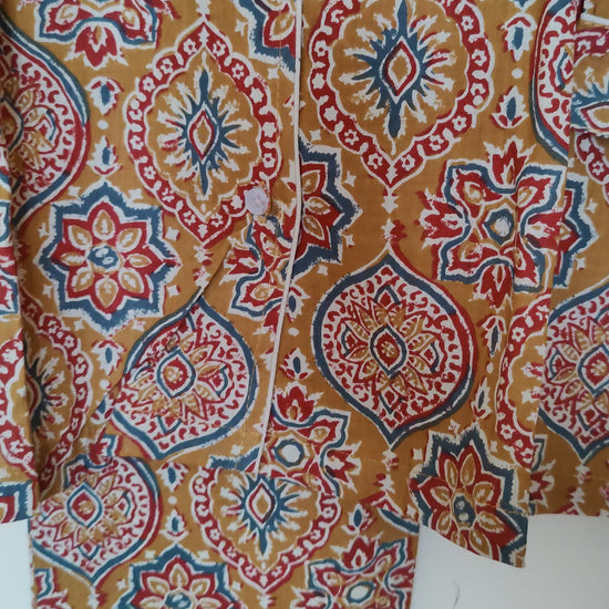 close up video of mustard ajrakh print Dharti pjs hanging on a wall.